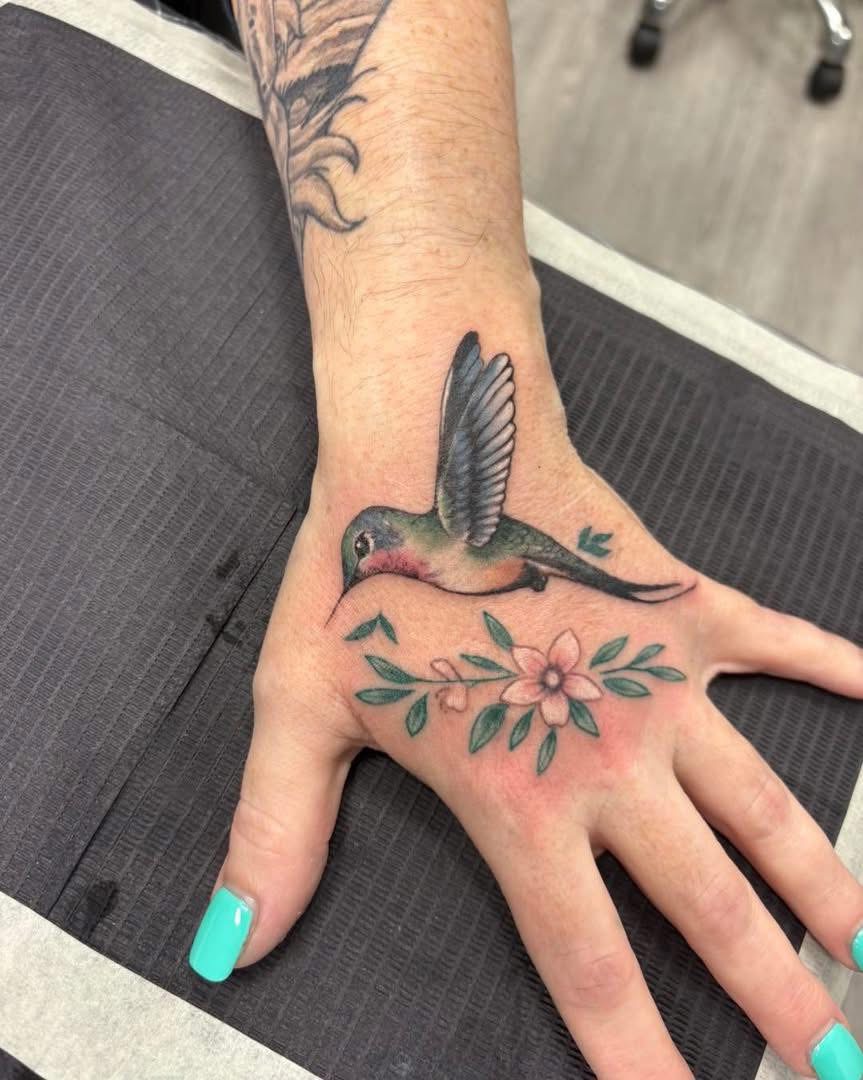 Color hummingbird and flowers tattoo on a hand