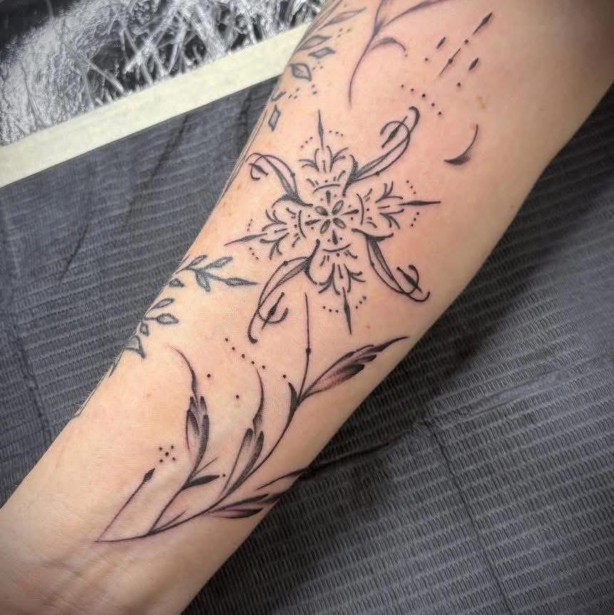 Fine-line lily and vine tattoo wrapping a forearm