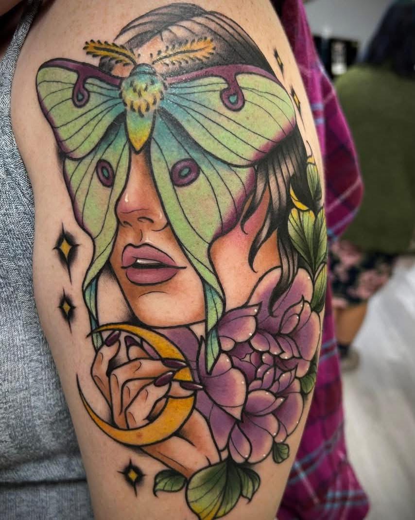 Color luna moth and portrait tattoo with peonies on an upper arm