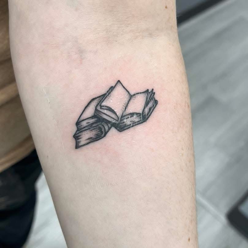 Small blackwork open books tattoo on a forearm