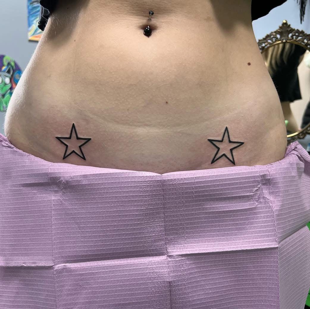 Matching outlined star tattoos on the hips