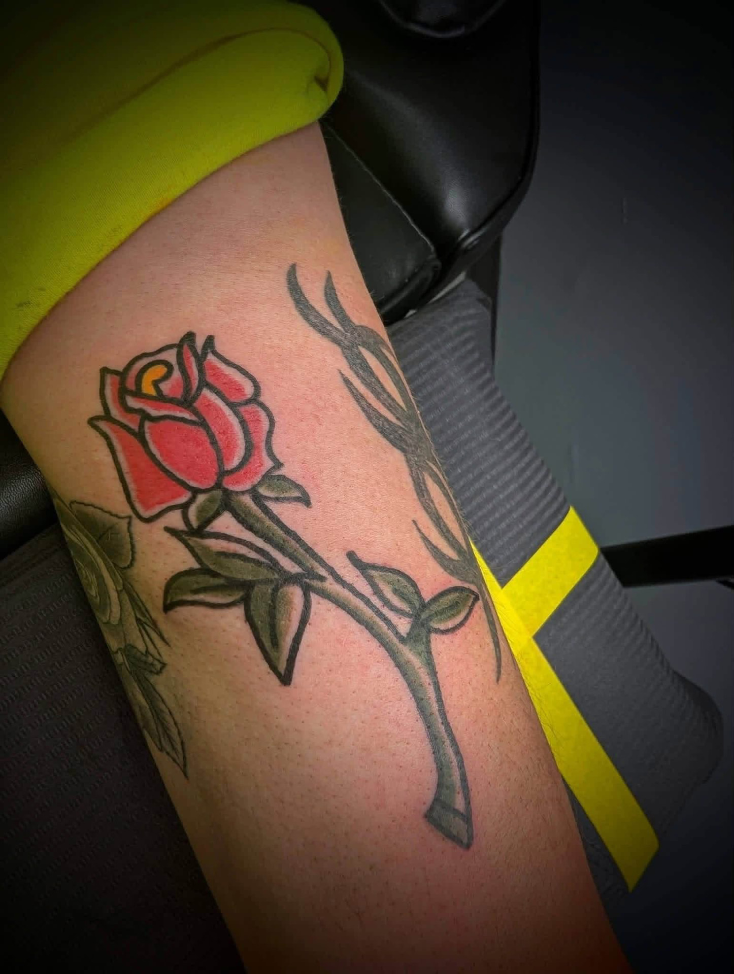 Traditional red rose with thorned stem tattoo on an arm