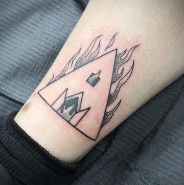 Small blackwork diamond and flame tattoo on an ankle