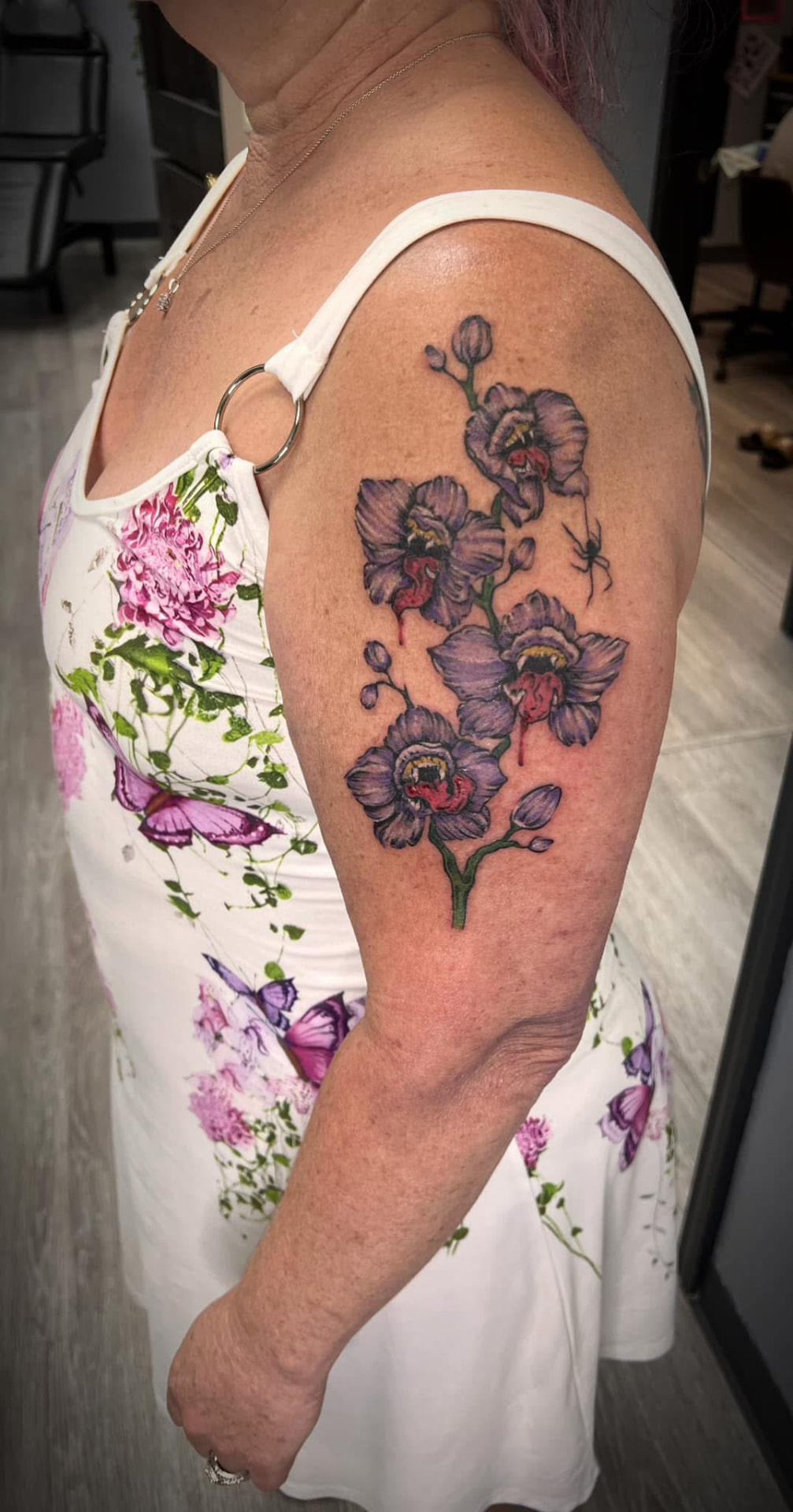 Purple orchid tattoo in full color on an upper arm