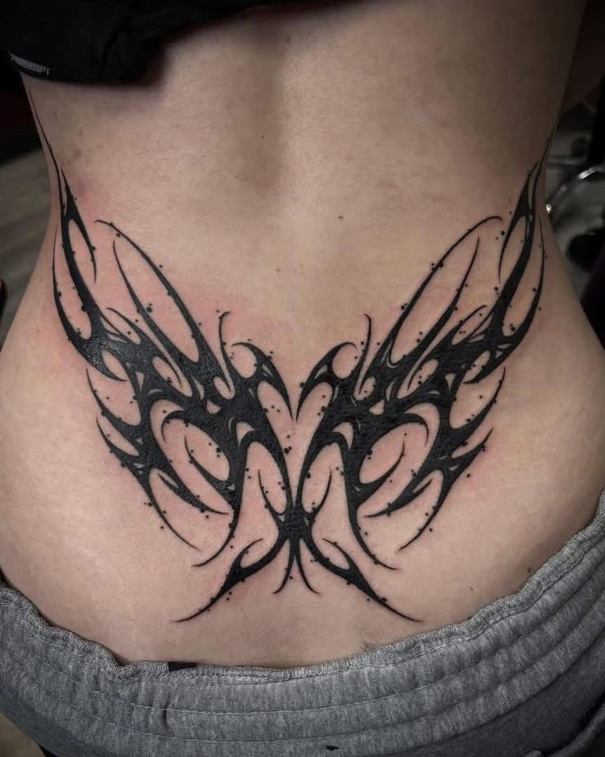 Bold blackwork tribal butterfly across the lower back
