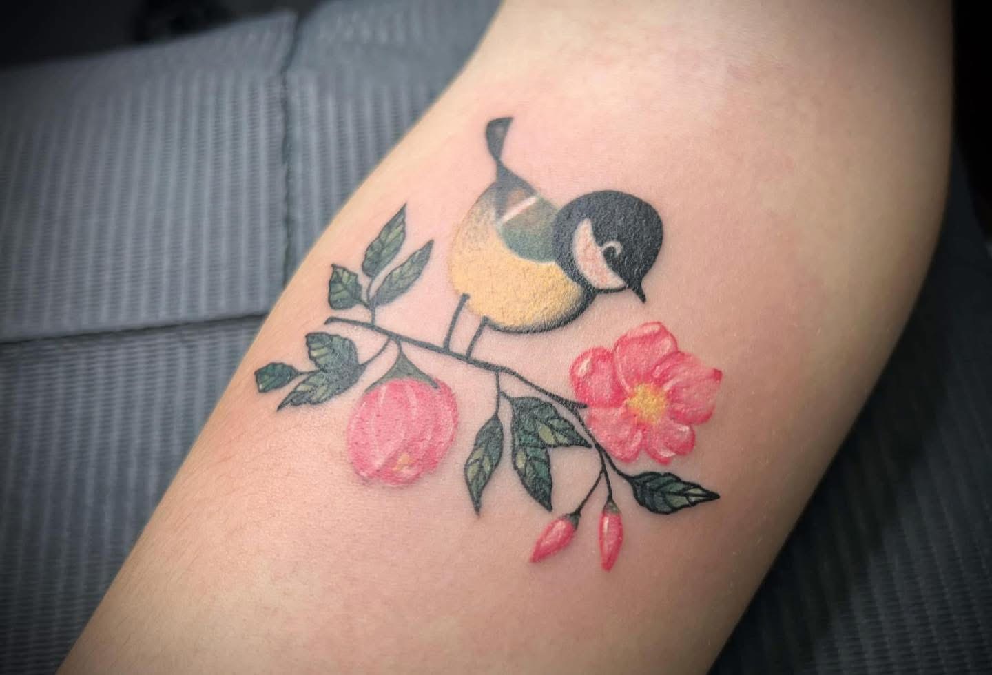 Color tattoo of a songbird on a blossoming branch
