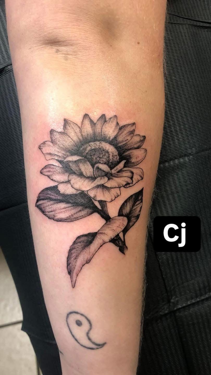 Black and grey sunflower tattoo on a forearm