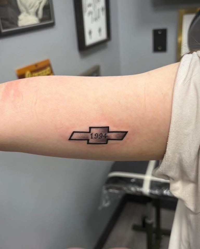 Small black and grey Chevy bowtie tattoo with 1994