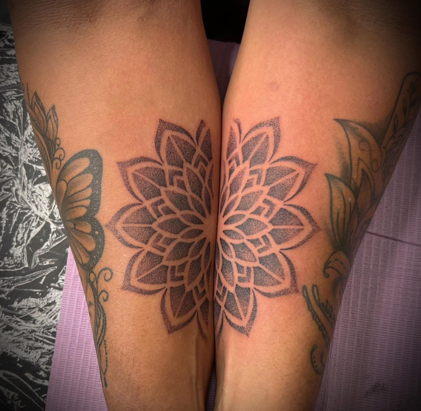 Matching dotwork mandala tattoos across two forearms